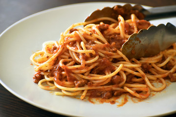 Spaghetti Bolognese with minced beef, onion, chopped tomato, garlic, olive oil, stock cube, tomato puree and Italian herb. Traditional Italian food in white plate. Selective focus.