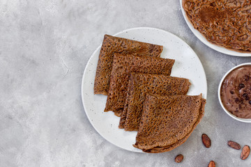 Sweet breakfast or dessert: chocolate crepes (thin pancakes) and chocolate cream. Copy space, top view.