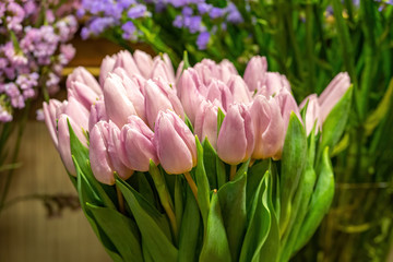 Fototapeta premium Pink tulips in flower shop with other flowers at the background. Bouquet of flowers for sale.