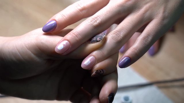 Closeup view 4k video of process of doing modern trendy two colors manicure. Professional manicurist adding cute drawing to fresh naildesign.