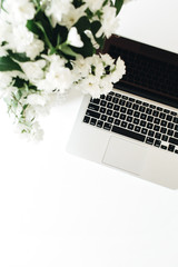 Laptop and flowers bouquet on white table. Flatlay, top view minimal background.