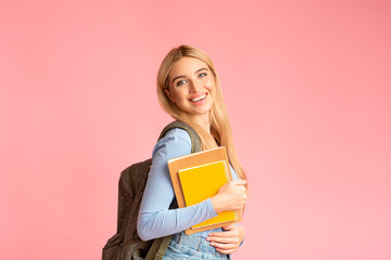 Teenager wearing backpack holding notebooks at studio