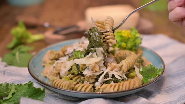 Cime di rapa pasta in a plate on with parmesan on a wooden table. Traditional food of the south of Italy, from Puglia