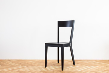 modern black chair on a wooden flor in front of white background