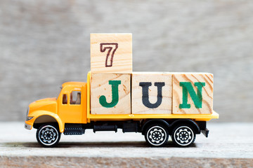 Truck hold letter block in word 7jun on wood background (Concept for date 7 month June)