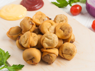 deep-fried dumplings on a wooden Board with tomato and cheese sauce