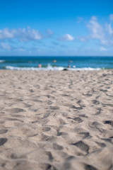 Sandy beach facing the bright blue ocean with cloudy blue sky