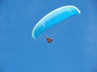 Man is paragliding in front of blue sky