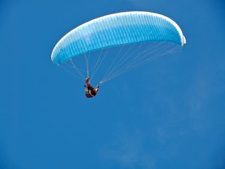 Man is paragliding in front of blue sky