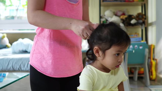mum hair tie her daughter at home.
