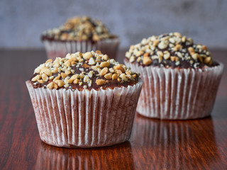 Three muffins with peanuts and chocolate glaze in line. Selective focus. Close-up.