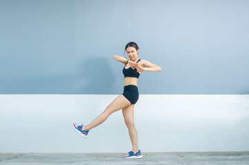 Beautiful young athletes are jumping in front of the indigo or gray and white background. She is bright and very happy.