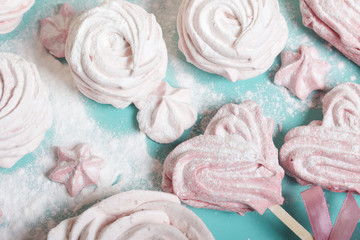 Obraz na płótnie Canvas Delicate pink marshmallows of various shapes. Lies on a turquoise tray. Sprinkled with icing sugar.