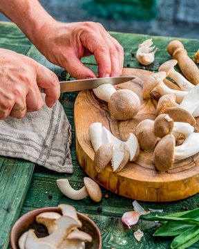 Fresh mushrooms sliced ​​on a wooden board, around garlic and sage leaves