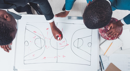 Basketball management. Defense attack tactic. Two African male coaches discussing game strategy.