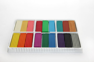 Naklejka premium plasticine of different colors in a box on a white background