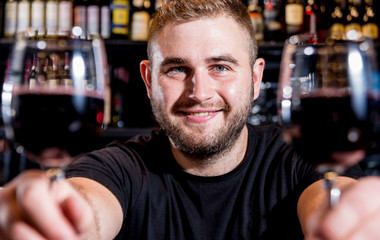 Bartender pours red wine into a glass. Sommelier. Restaurant. Nightlife