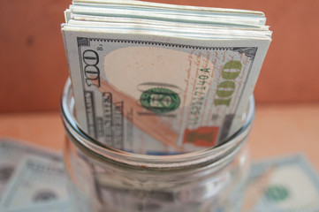 pack of money in a glass. jar full of dollars.