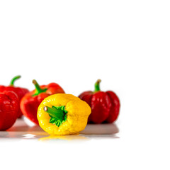 Textured multicolored peppers with green tails lie on a white background