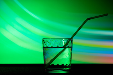 glass with a drink in green club light.