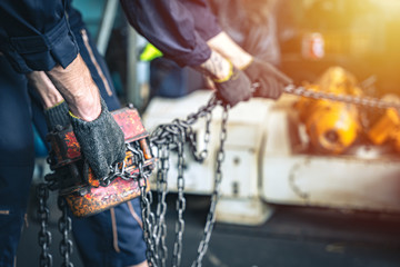 Male workers pulling chain attached to the hoist.