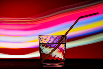 glass with a drink and a tube in club light.