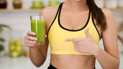 Woman pointing at glass of vegetable detox smoothie