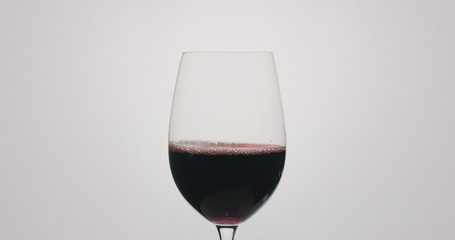 red wine pour into wineglass on neutral background