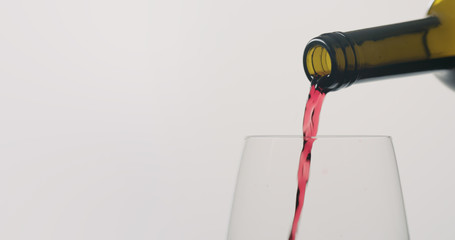 red wine pour into wineglass on neutral background
