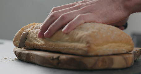 closeup of slicing freshly bakled ciabatta bread on olive board