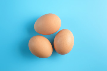 Three fresh brown chicken eggs on a blue background. Healthy good nutrition. Natural organic farm products.