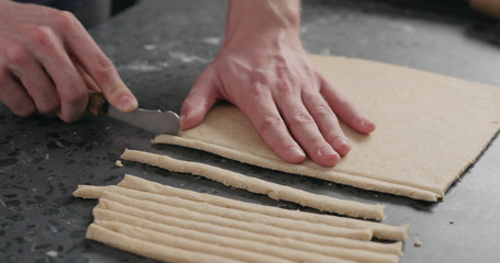 man cutting flat dough with knife