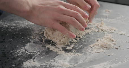 man working with dough on concrete countertop