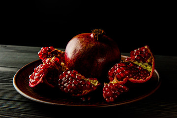 pomegranate fruit on a plate on a dark wooden background.