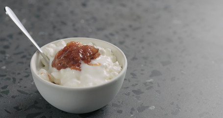 cottage cheese with fig marmalade and yogurt in white bowl on concrete surface