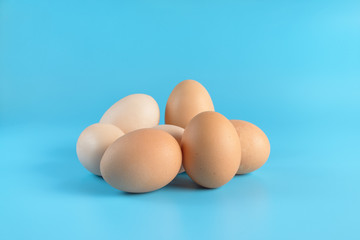 Seven fresh brown chicken eggs on a blue background. Healthy good nutrition. Natural organic farm products.