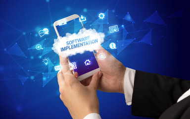 Female hand holding smartphone with SOFTWARE IMPLEMENTATION inscription, cloud technology concept