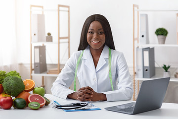 Smiling doctor nutritionist with vegetable and fruit in office