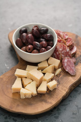 Italian antipasti with cheese olives and sausage on olive wood board