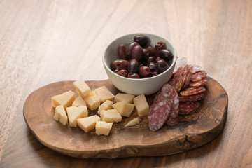 Italian antipasti with cheese olives and sausage on olive wood board