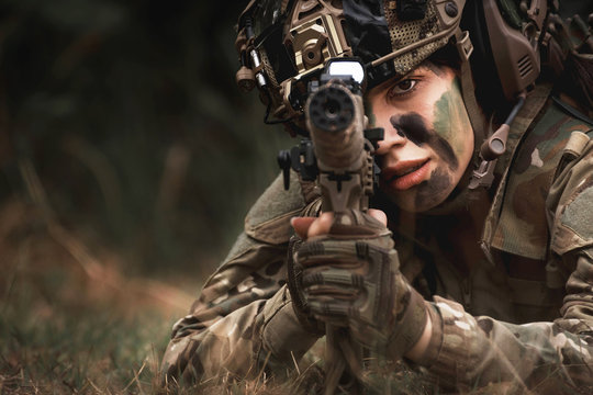 close up of woman soldier holding gun laying on the ground
