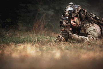 close up of woman soldier holding gun laying on the ground