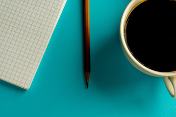notebook, pencil and cup of coffee on a blue background.