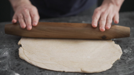 Fototapeta na wymiar man rolling dough on concretre countertop