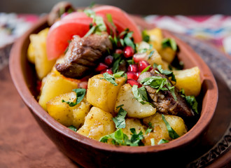 Fried potatoes with pieces of meat in a clay pot. European cuisine.