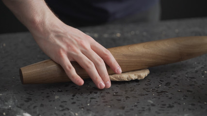 man rolling dough on concretre countertop