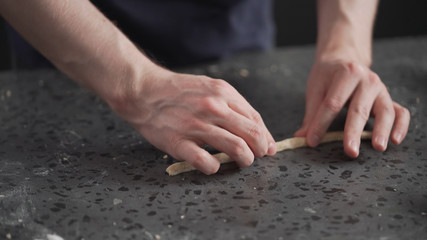 man making grissini on concretre countertop