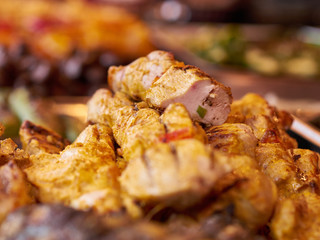 Close-up of grilled chicken meat on tray at street food festival, selective focus. Unhealthy oily barbeque street fast food for meat lovers concept