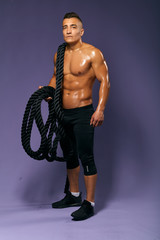 Fototapeta na wymiar sexy shirtless man holding battle ropes, full length photo. isolated blue background, studio shot, sportsman holding sport equipment and looking at the camera , full length photo, isolated blue
