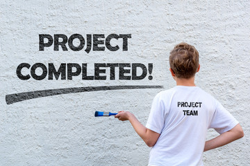 Junge vor einer verputzten weißen Wand mit dem Schriftzug PROJECT COMPLETED und Platz für Text